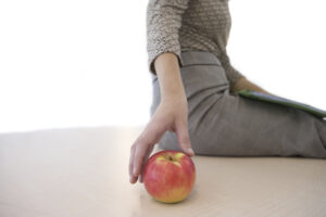 Businesswoman with apple, mid section, cut out