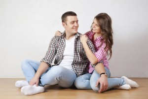 Portrait Of Happy Young Couple Sitting On Floor Looking Up Ready for your text or product